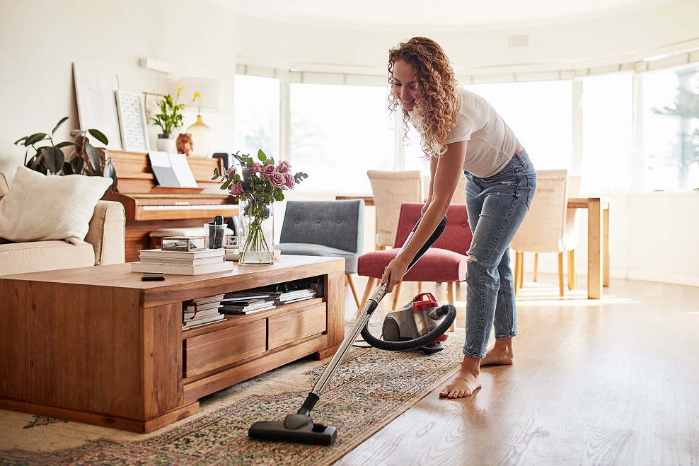 Young woman vacuuming the livingroom
