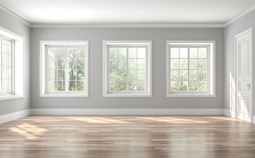 A room with soft gray walls and white trim around the windows