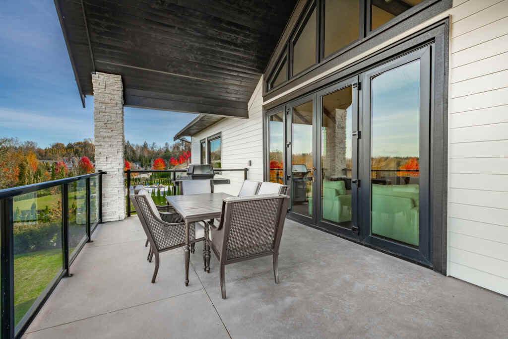 Exterior covered deck on a very luxurious estate home with patio furniture and a fireplace on a blue sky day