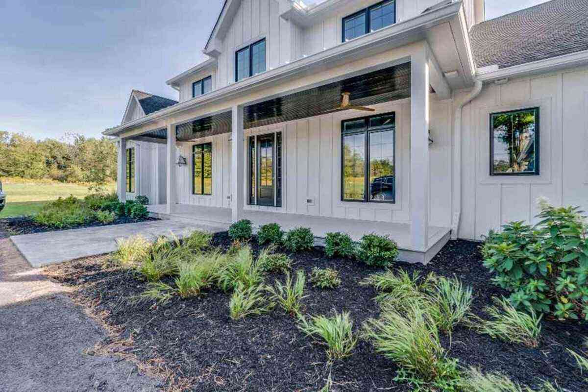 A white farmhouse featuring beautiful bay windows and a landscaped yard in Columbus, OH