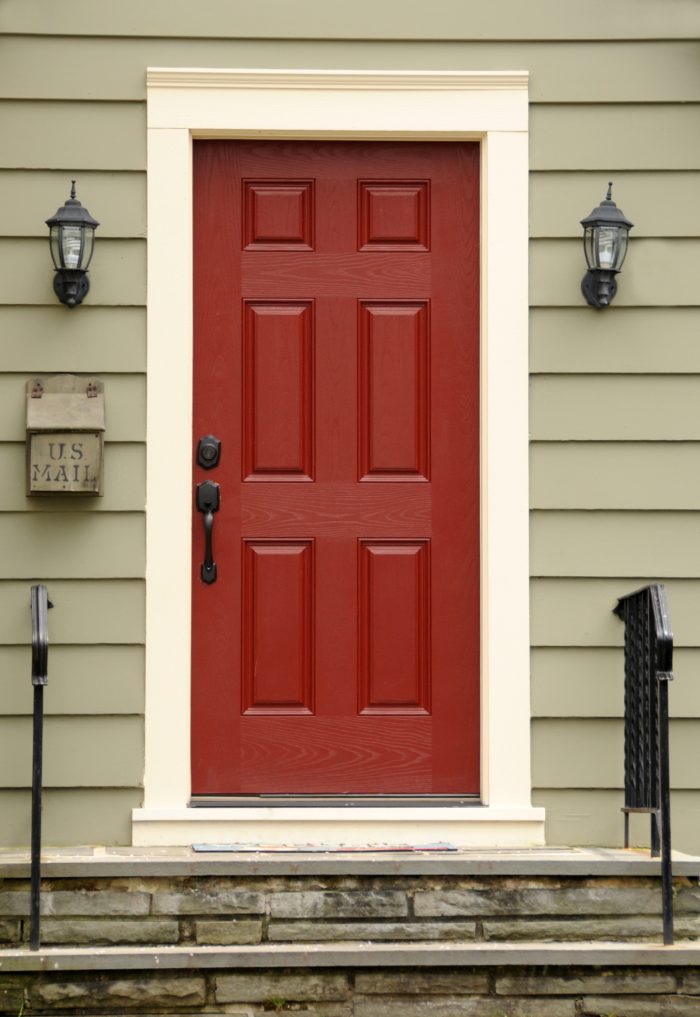 Red front entry door with decorative panels installed on a home